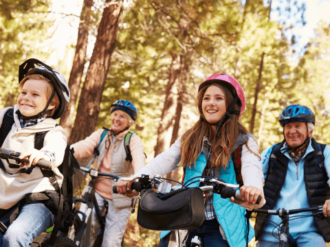 Grootouders fietsen met hun kleinkinderen door het bos